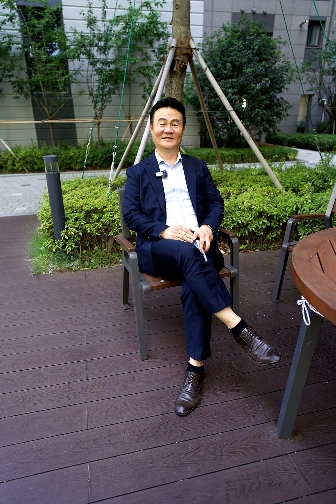 단지 내 조경 공간의 벤치에 앉아 있는 이용우 본부장